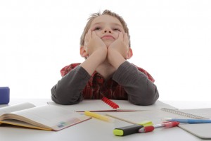 enfant graçon rêvant au lieu de faire ses devoirs